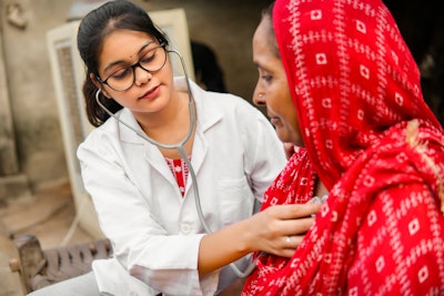 Indian doctor uses a stethoscope on an Indian woman.