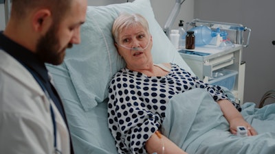 Image of a doctor and a woman in a hospital bed with oxygen tubes in her nose.