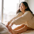 This is a photo of a young, Asian woman waking up refreshed and strecthing.