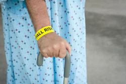 Image of a patient with their hand on a cane and wearing a fall risk bracelet.
