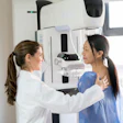 This is a photo of a female health care worker helping an Asian woman with a mammogram.