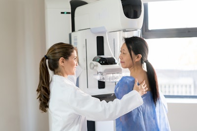 This is a photo of a female health care worker helping an Asian woman with a mammogram.