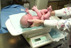 Image of a newborn baby being weighed on a scale.