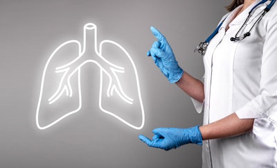 Image of female doctor holding up gloved hands to a neon outline of lungs.