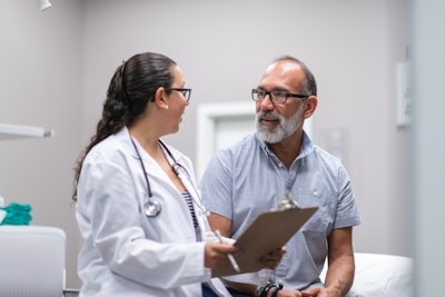 Woman doctor with a clipboard surveying a male patient.