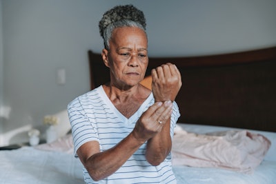 Older woman rubbing her arthritic wrist.