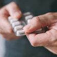 Hands holding white medication blister pack with pills