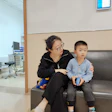 Woman comforting young boy while sitting together in medical waiting area