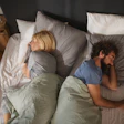 Couple sleeping peacefully in bed with gray and white bedding, viewed from above