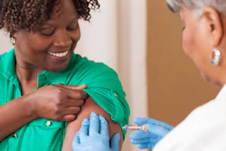 Healthcare worker in green scrubs administering vaccine injection to patient's arm