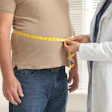 Doctor measuring patient's waist with yellow tape measure during health checkup