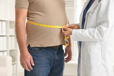 Doctor measuring patient's waist with yellow tape measure during health checkup