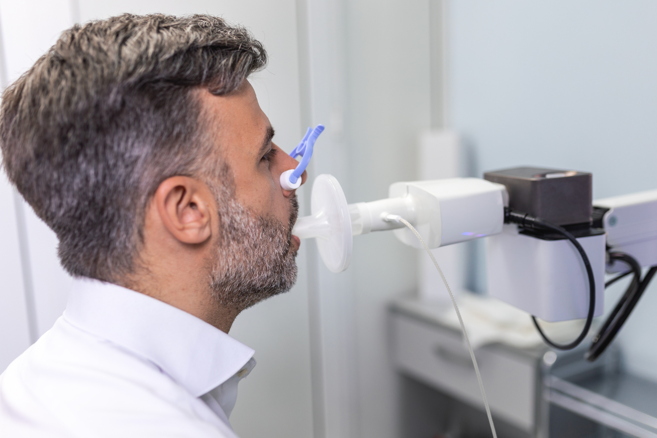 Man performing spirometry test with blue mouthpiece during pulmonary function assessment in medical clinic