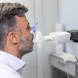 Man performing spirometry test with blue mouthpiece during pulmonary function assessment in medical clinic